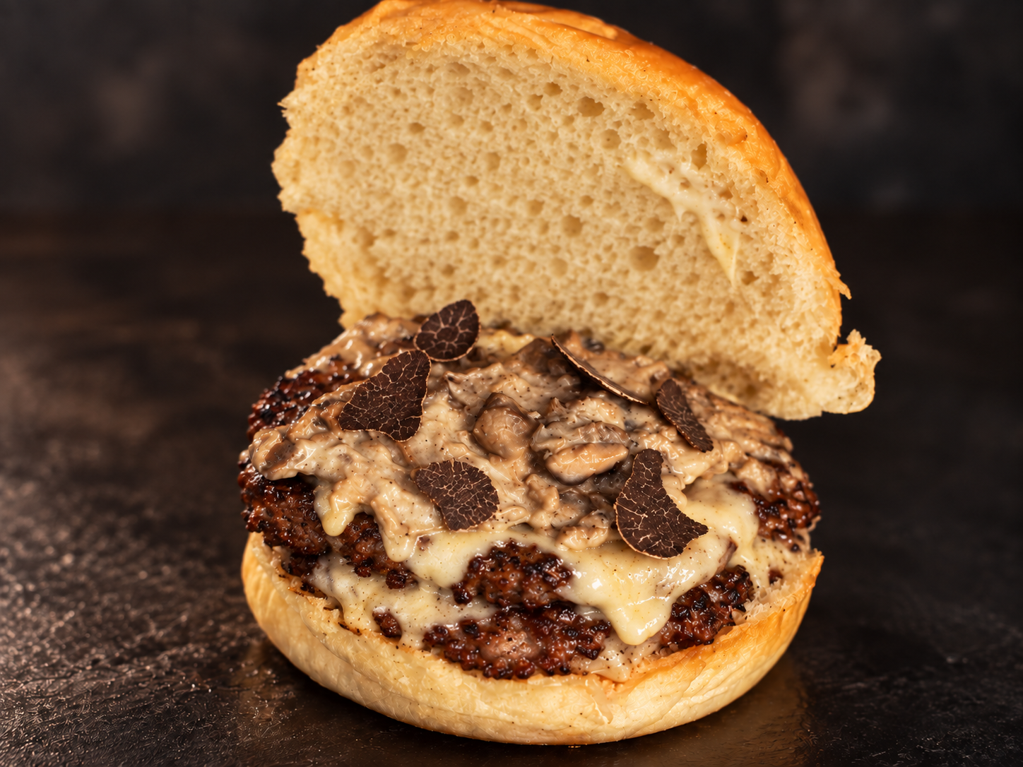 Burger close-up with creamy mushrooms and black truffle shavings